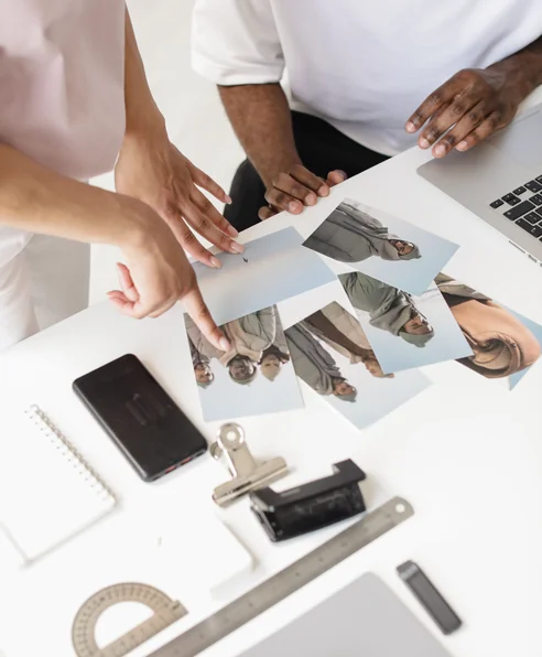 http://Hands%20laying%20out%20printed%20photographs%20across%20a%20desk%20while%20selecting%20images